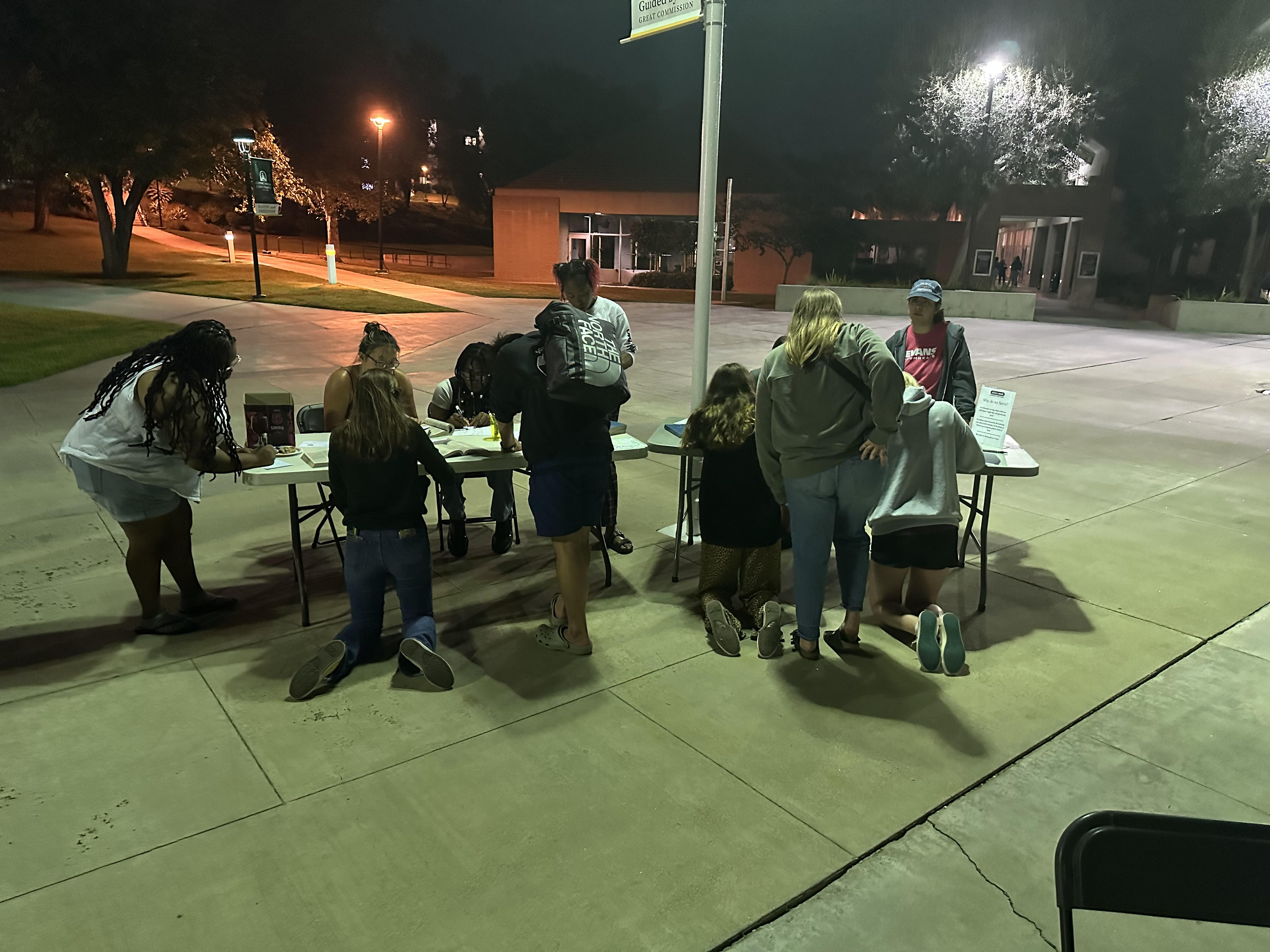 Students helping each other fold blankets on tables set up in front of CU Center.